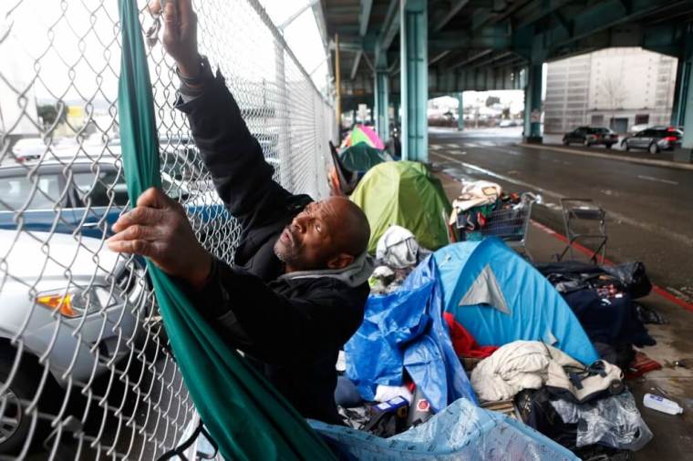 Jonathan Payne, a homeless man, takes down tarps he had used to protect his possessions during an El Nino driven storm in San Francisco, California, January 6, 2016.