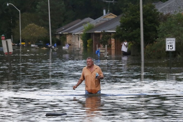 A man wades through a flooded street in Ascension Parish, Louisiana, U.S., August 15, 2016.