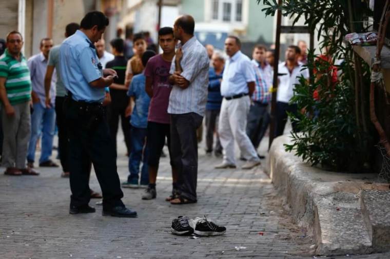 A police officer secures the scene of an explosion as locals stand next to him after a suspected suicide bomber targeted a wedding celebration in the Turkish city of Gaziantep, Turkey, August 21, 2016.