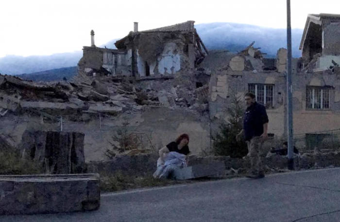 People stand by a road following a quake in Amatrice, central Italy, August 24, 2016.