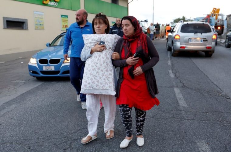 People walk along the road following a quake in Amatrice, central Italy, August 24, 2016.