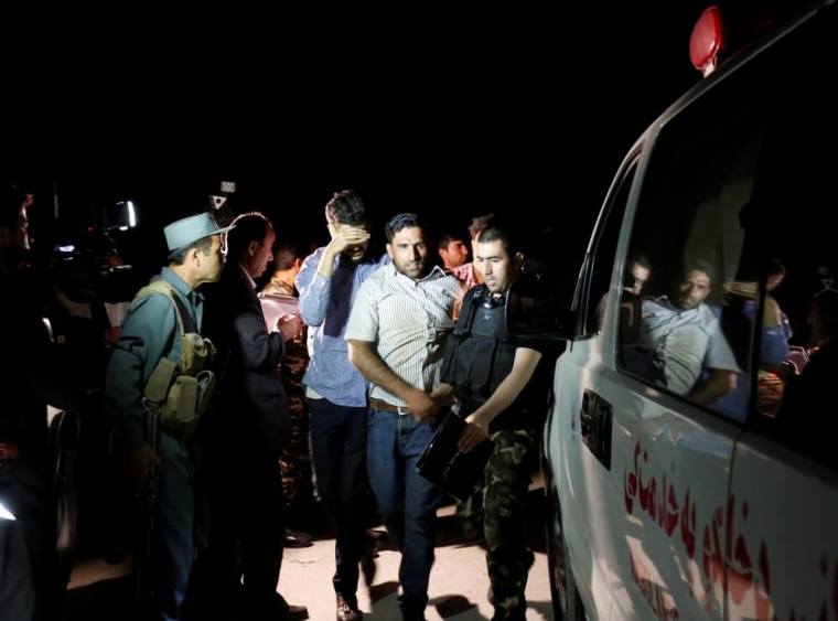 Afghan men walk towards an ambulance after they were rescued from the site of an attack at American University of Afghanistan in Kabul, Afghanistan, August 24, 2016.