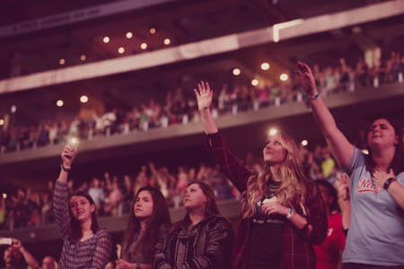 A group of young women worship together at the Harvest SoCal event in Anaheim, California, on Friday, August, 27, 2016.